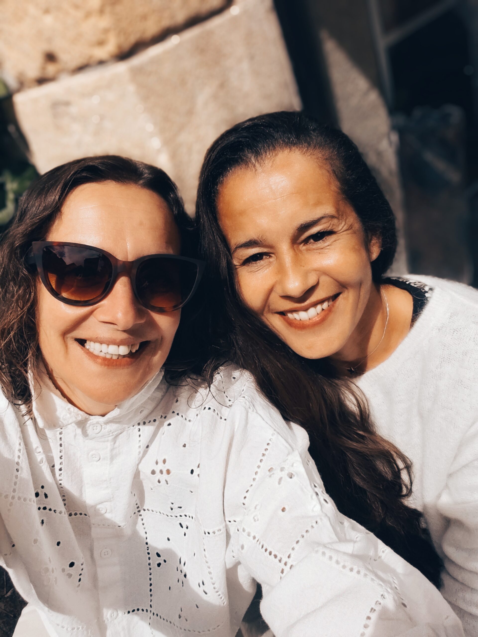 Portrait de deux femmes souriantes en chemises blanches brodées