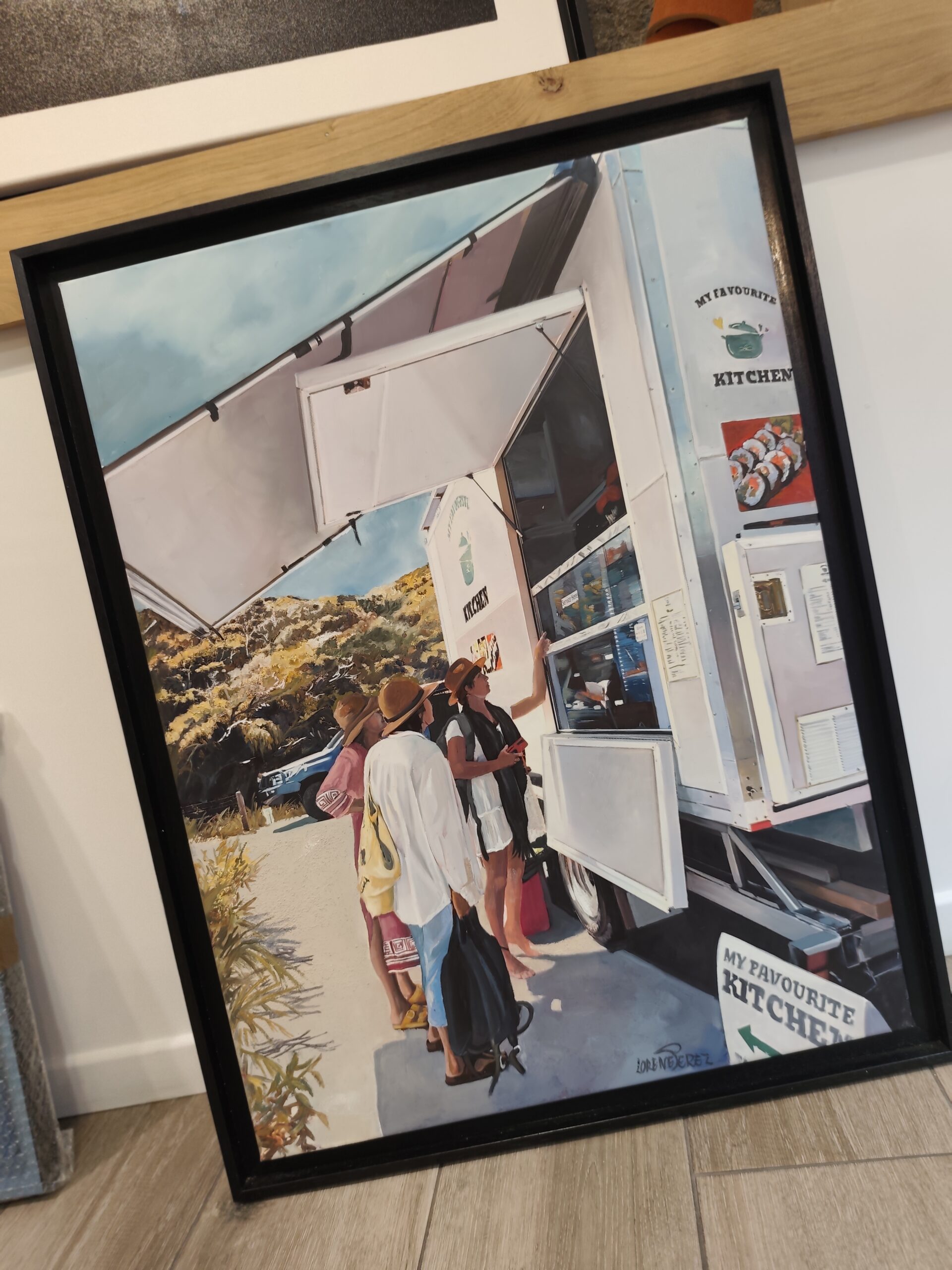 Tableau d’un food truck dans son cadre noir, posé contre un mur