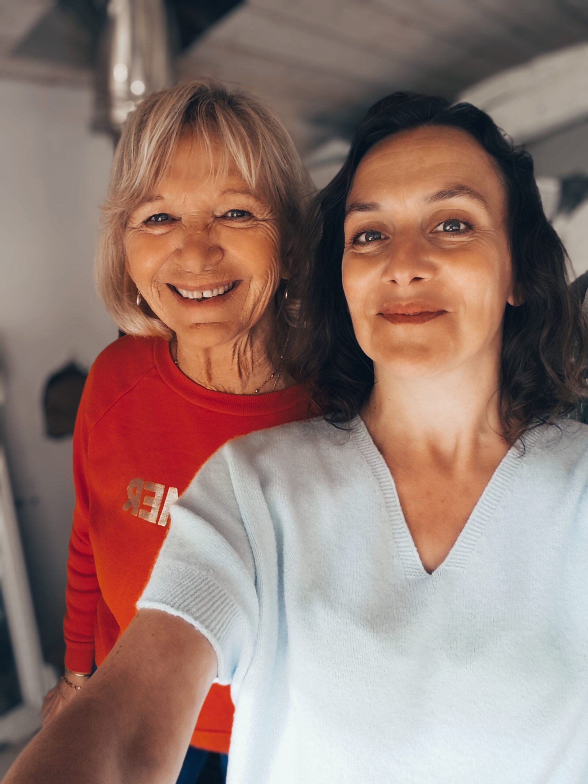 Portrait de deux femmes souriantes, en pull rouge et en pull bleu ciel